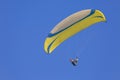 A yellow paraglider gliding across a clear blue sky Royalty Free Stock Photo