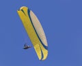 A yellow paraglider gliding across a clear blue sky Royalty Free Stock Photo