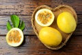 Yellow passion fruit and passion fruit cut in half in heart-shaped basket on wooden table