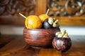 Yellow passion fruits and mangosteen in wooden bowl. One mangosteen lying near bowl. Mix of exotic fresh fruits from Bali, Asia