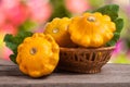 Yellow pattypan squash with leaf in a wicker basket on wooden table blurred background