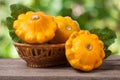 Yellow pattypan squash with leaf in a wicker basket on wooden table blurred background Royalty Free Stock Photo