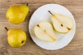 Yellow pears and halves of pear in plate on table