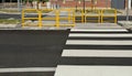 Yellow pedestrian barriers in the traffic island on a four lane street. Crosswalk on both sides and sidewalk on behind. Royalty Free Stock Photo