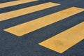 Yellow pedestrian crossing on black pavement