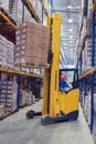 Yellow pedestrian stacker lifts pallet with boxes on the shelves Royalty Free Stock Photo