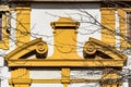 Yellow pediment over a doorway in curved and broken-apex style.