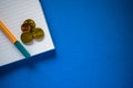 Yellow pen and some Euro money coins on white notepad