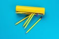 Yellow pencil case with yellow pencils and pens on a blue background. Flat lay Royalty Free Stock Photo