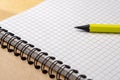 Yellow pencil on a notebook with sheets in a cage on a wooden table. Concept for shopping list, notes, planning. Side Royalty Free Stock Photo