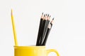 Yellow pencil separated in yellow cup with black pencils still l Royalty Free Stock Photo