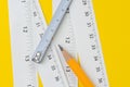 Yellow pencil and white measuring tapes with centimetre and inches on vivid yellow background, length, long or maker instrument