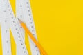 Yellow pencil and white measuring tapes with centimetre and inches on vivid yellow background, length, long or maker instrument