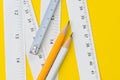 Yellow pencil and white measuring tapes with centimetre and inches on vivid yellow background, length, long or maker instrument