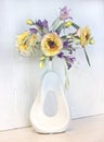 Yellow peonies and irises in a white vase. Artificial silk flowers in the interior Royalty Free Stock Photo