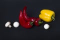Yellow pepper and red pepper with mushrooms on a black background. Royalty Free Stock Photo