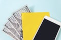 Yellow a piece of paper, 100 dollar bills and empty screen mobile phone on blue background Royalty Free Stock Photo