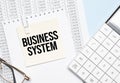 a yellow piece of paper with the text business system and the calculator are lying on the notepad Royalty Free Stock Photo