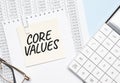 a yellow piece of paper with the text Core Values and the calculator are lying on the notepad Royalty Free Stock Photo