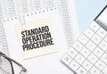 a yellow piece of paper with the text Standard Operation Procedure and the calculator are lying on the notepad