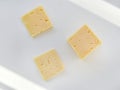 Yellow pieces of cheese on a white background. Square cheese. Delicious cheese snack Royalty Free Stock Photo