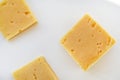 Yellow pieces of cheese on a white background. Square cheese. Delicious cheese snack Royalty Free Stock Photo