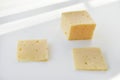 Yellow pieces of cheese on a white background. Square cheese. Delicious cheese snack Royalty Free Stock Photo