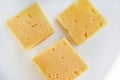 Yellow pieces of cheese on a white background. Square cheese. Delicious cheese snack Royalty Free Stock Photo