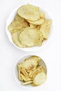 Yellow pieces of fried potatoes in a plate. Salted chips on a white background