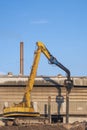 Yellow Pile drilling crawler crane working to install foundation near the old factory building in industrial construction site Royalty Free Stock Photo