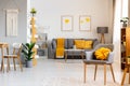 Yellow pillow on grey armchair in spacious flat interior with po Royalty Free Stock Photo