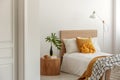 Yellow pillows and blanket on white single wooden bed