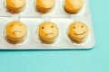 Yellow pills andfunny faces in a blister on a blue background. The concept of antidepressants and healing