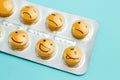 Yellow pills andfunny faces in a blister on a blue background. The concept of antidepressants and healing