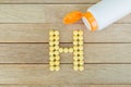 Yellow pills forming shape to H alphabet on wood background