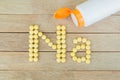 Yellow pills forming shape to Na alphabet on wood background