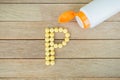 Yellow pills forming shape to P alphabet on wood background Royalty Free Stock Photo