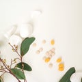 Yellow pills with green leaves and white stones on a white background. Medicine, beauty, health. A place for text. Royalty Free Stock Photo