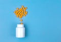 Yellow pills and plastic white bottle. Blue background with copy space for text Royalty Free Stock Photo