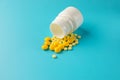 Yellow pills and plastic white bottle. Blue background with copy space for text Royalty Free Stock Photo