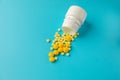 Yellow pills and plastic white bottle. Blue background with copy space for text Royalty Free Stock Photo