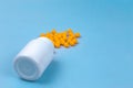 Yellow pills and plastic white bottle. Blue background with copy space for text Royalty Free Stock Photo