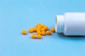 Yellow pills and plastic white bottle. Blue background with copy space for text Royalty Free Stock Photo