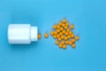 Yellow pills and plastic white bottle. Blue background with copy space for text Royalty Free Stock Photo