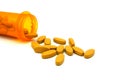 Yellow pills spilling or pour out of orange pill bottle isolated on white background Royalty Free Stock Photo