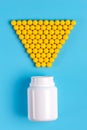 Yellow pills, tablets and white bottle on blue background