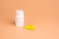 Yellow pills, tablets and white bottle on orange background Royalty Free Stock Photo