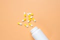 Yellow pills, tablets and white bottle on orange background Royalty Free Stock Photo