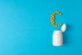 Yellow pills in a vitamin C poured from a medicine bottle on blue background. Medication and prescription pills. Top view. Flat la Royalty Free Stock Photo