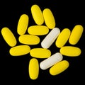 Yellow Pills and White Capsules on Black Background Royalty Free Stock Photo